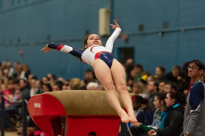 picture of a girl practicing gymnastics in front a lot of people wearing leotard 