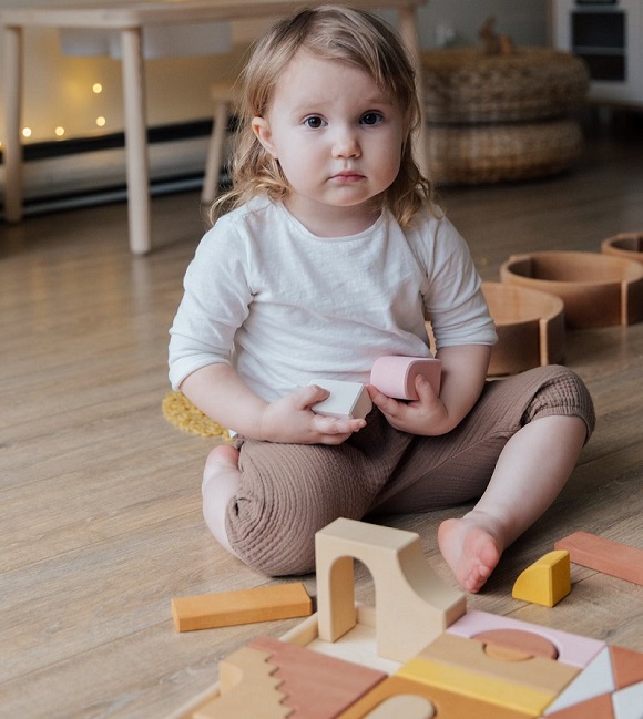 picture of a baby playing wit a wooden puzzle on a living room 