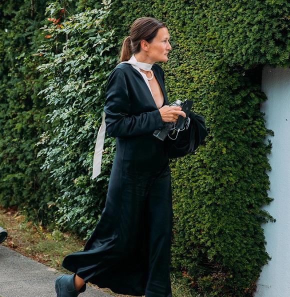 picture of a woman in long black dress walking on a sidewalk 