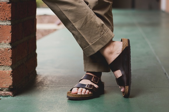 picture of men standing beside a wall wearing pants and Brikenstocks sandals