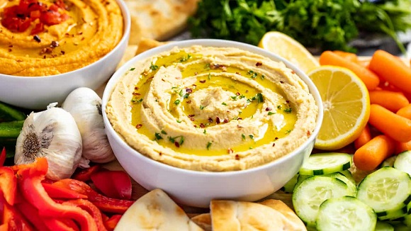 vegan hummus in a bowl surrounded by vegetables 