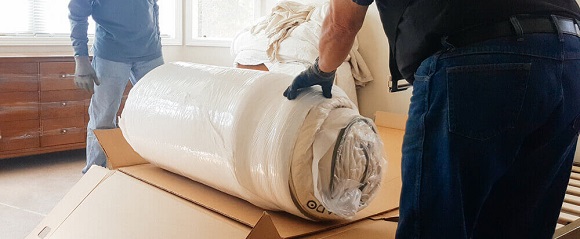 people unrolling a newly bought mattress from the box