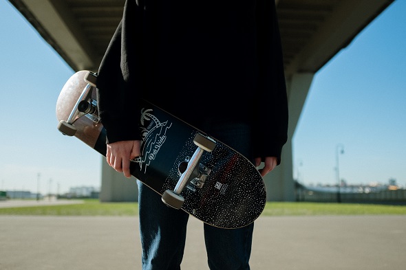 picture of person holding a skateboard under a bridge 