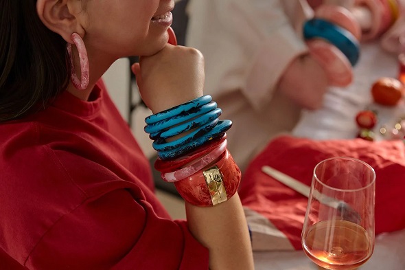 picture of a woman sitting on a table wearing red shirt and resin jewellery designer pieces