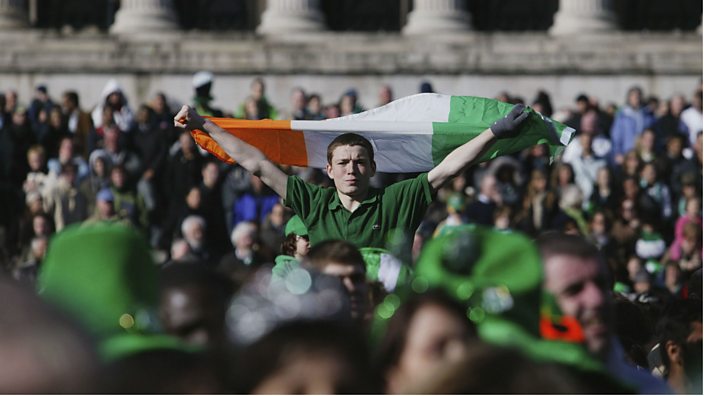 Man is holding ireland flag in the middle of the crowd 
